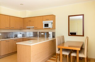 A modern kitchen with wooden cabinets, a microwave, a coffee maker, and a dining area with a table and chairs.