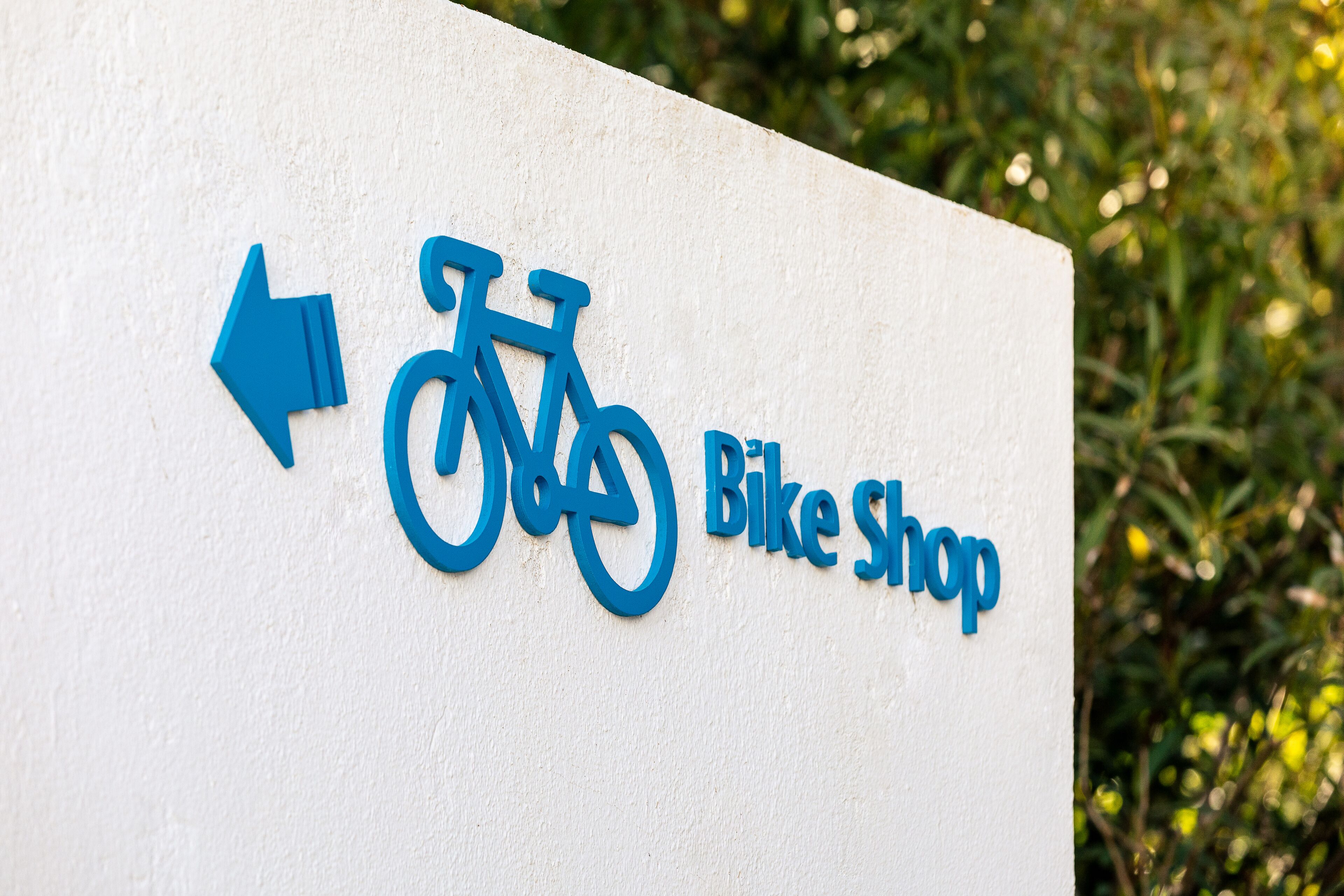 Un cartel con el símbolo de una bicicleta y el texto 'Bike Shop', que indica la ubicación de una tienda de bicicletas.
