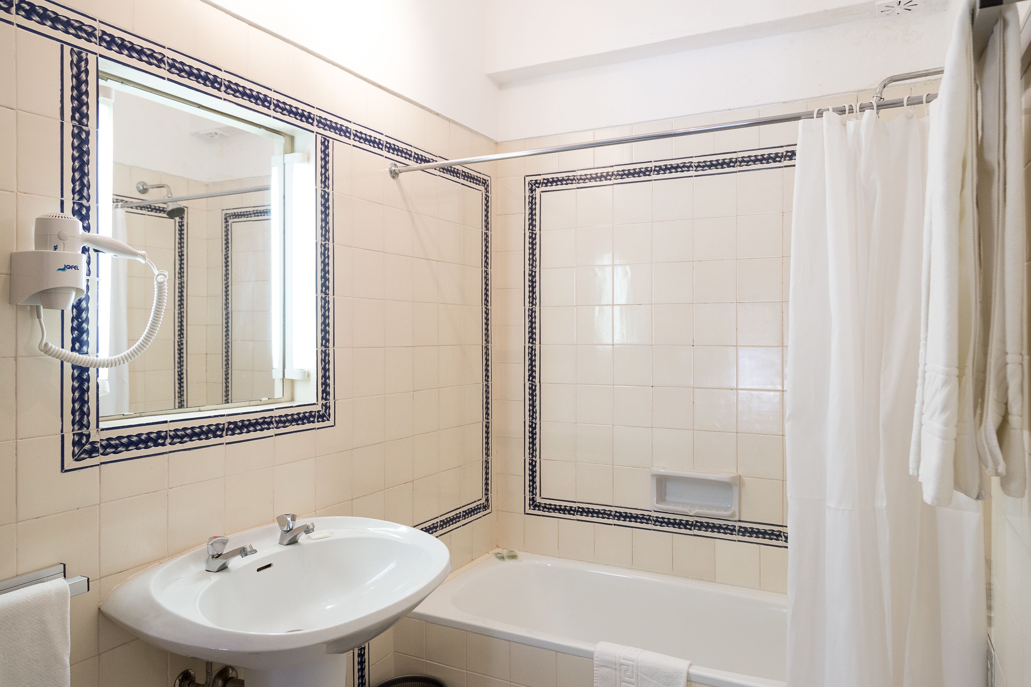 Un baño con un lavamanos blanco, un espejo y una bañera.