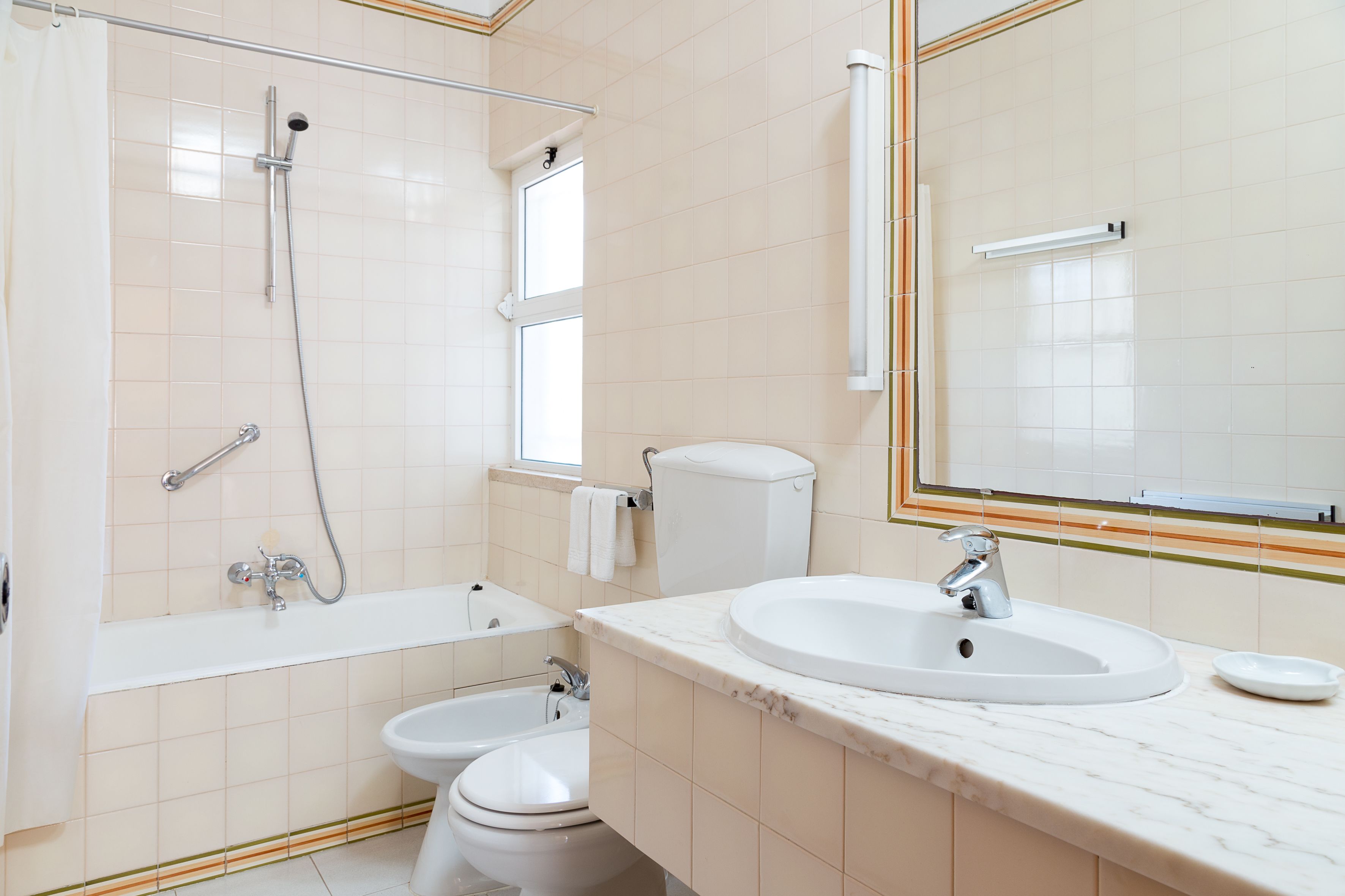 A modern bathroom with a bathtub, a sink, a toilet, and a bidet.