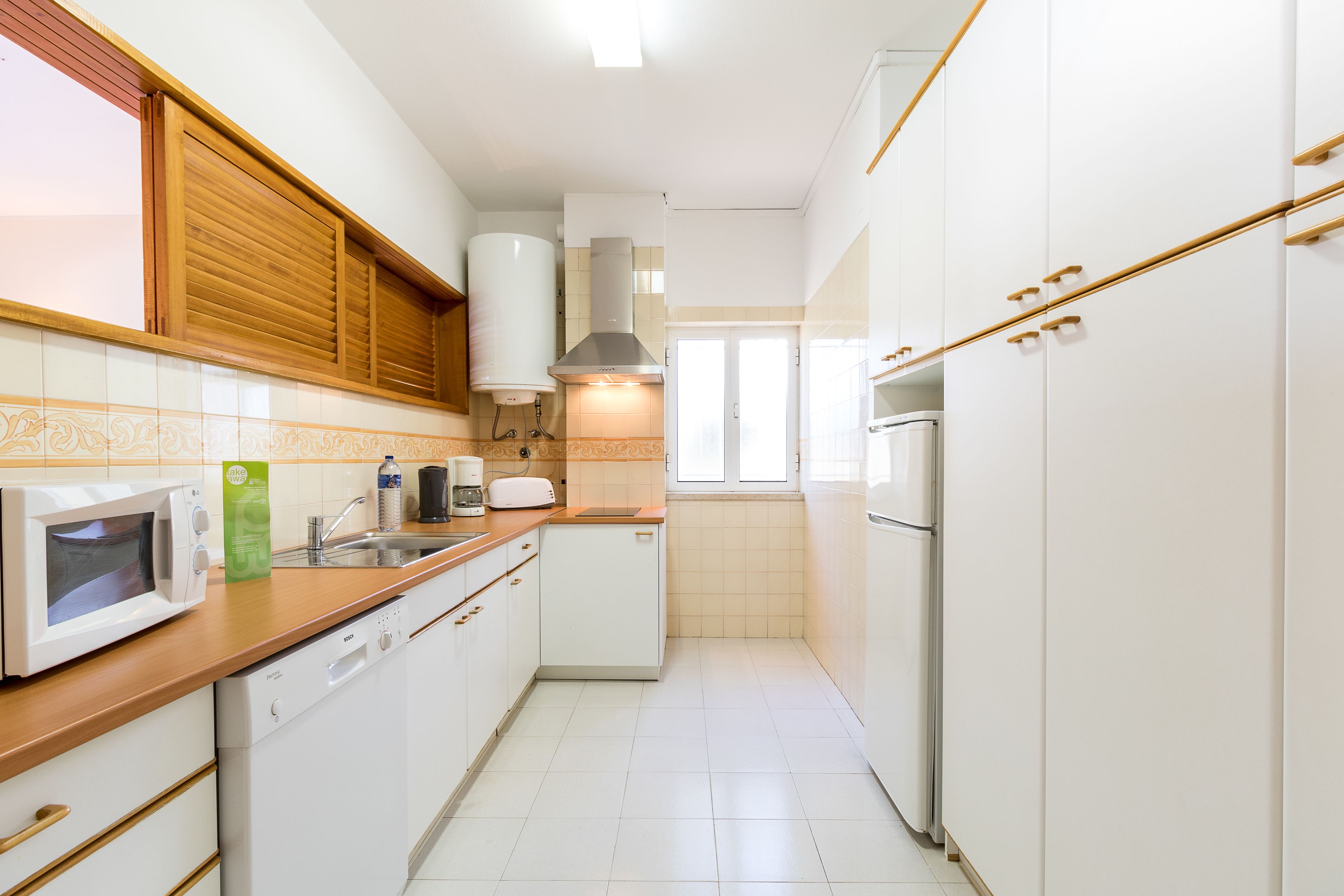 A kitchen with white cabinets, a microwave, a coffee maker, and a refrigerator.