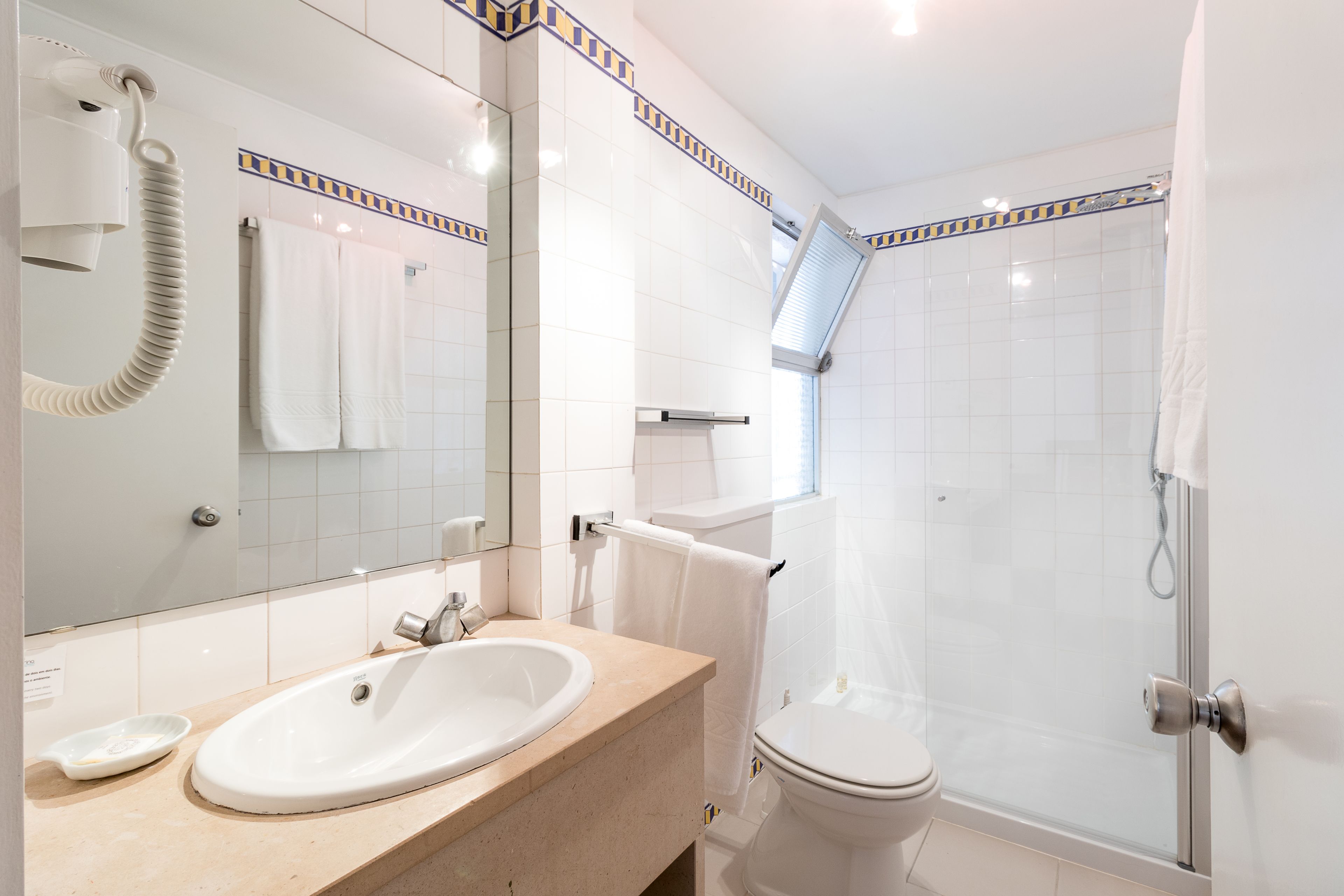 Een moderne badkamer met een wastafel, spiegel, handdoekrek en een douche met glazen wanden.