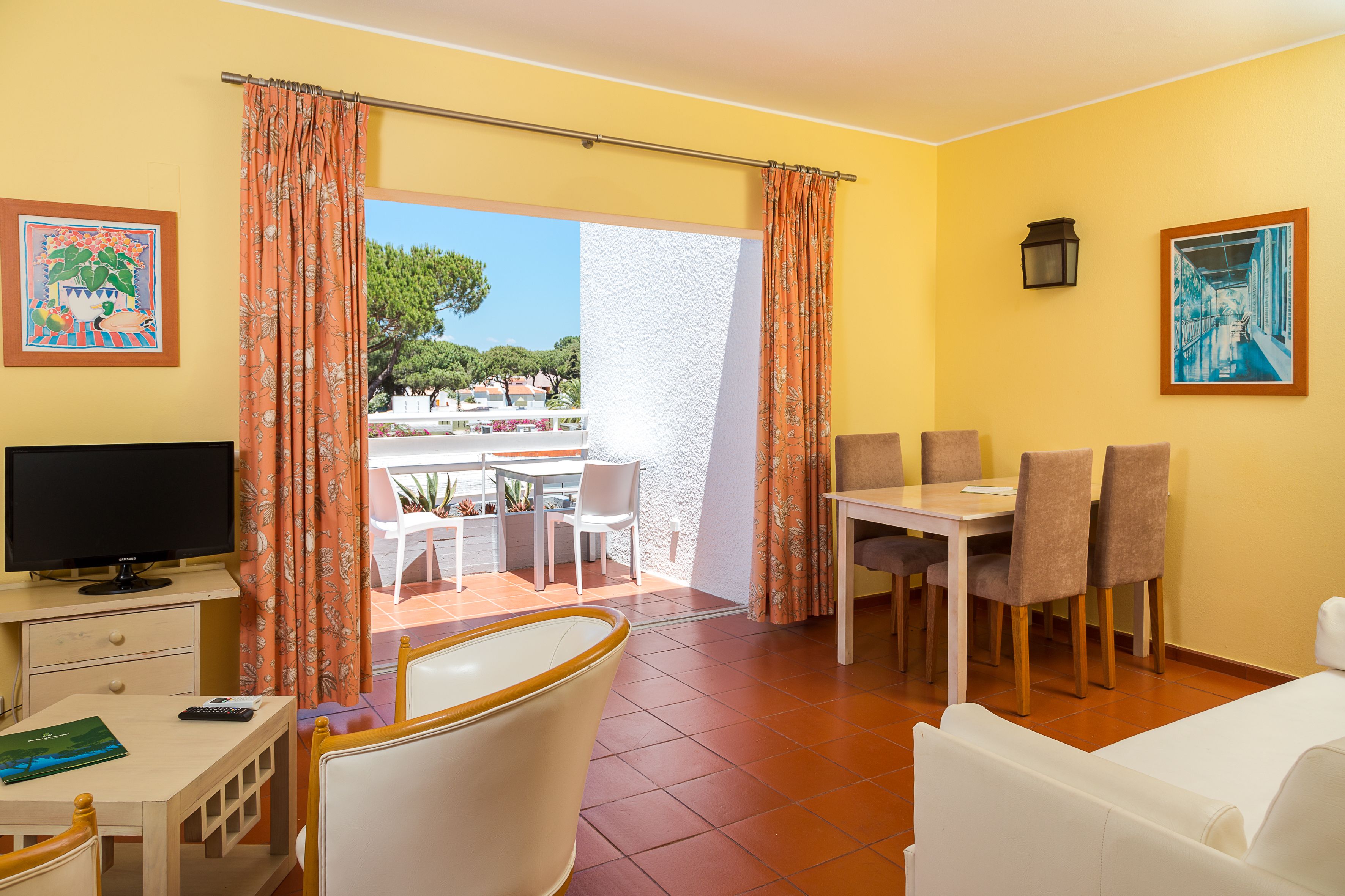 Une chambre d’hôtel avec un coin repas, une télévision et un balcon offrant une vue.