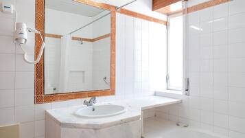 A bathroom with a white sink, mirror, and shower.