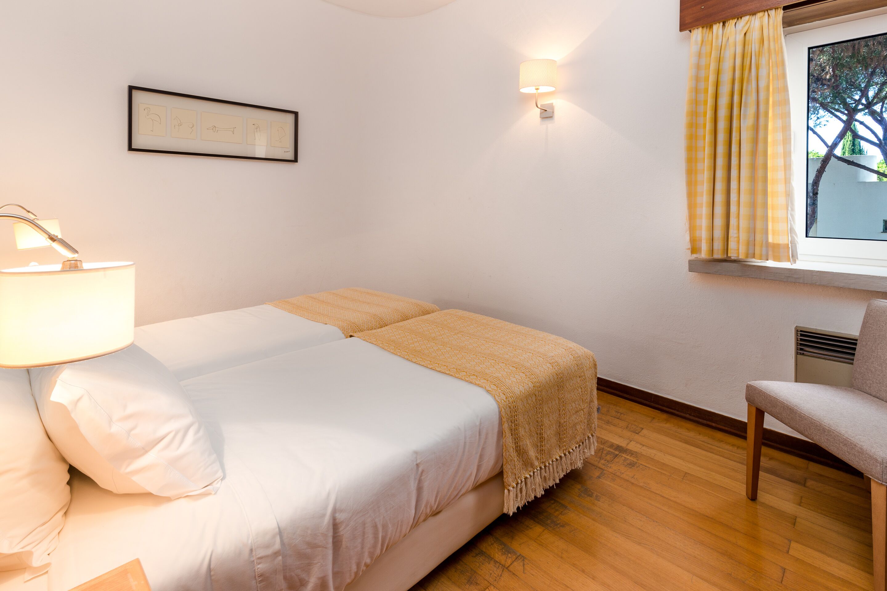 A bedroom with a bed, bedside lamp, and a window with curtains.