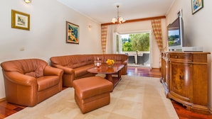A living room with a brown leather sofa, a wooden cabinet, and a television on a stand. - Hotel Dubrovnik (Dubrovnik)