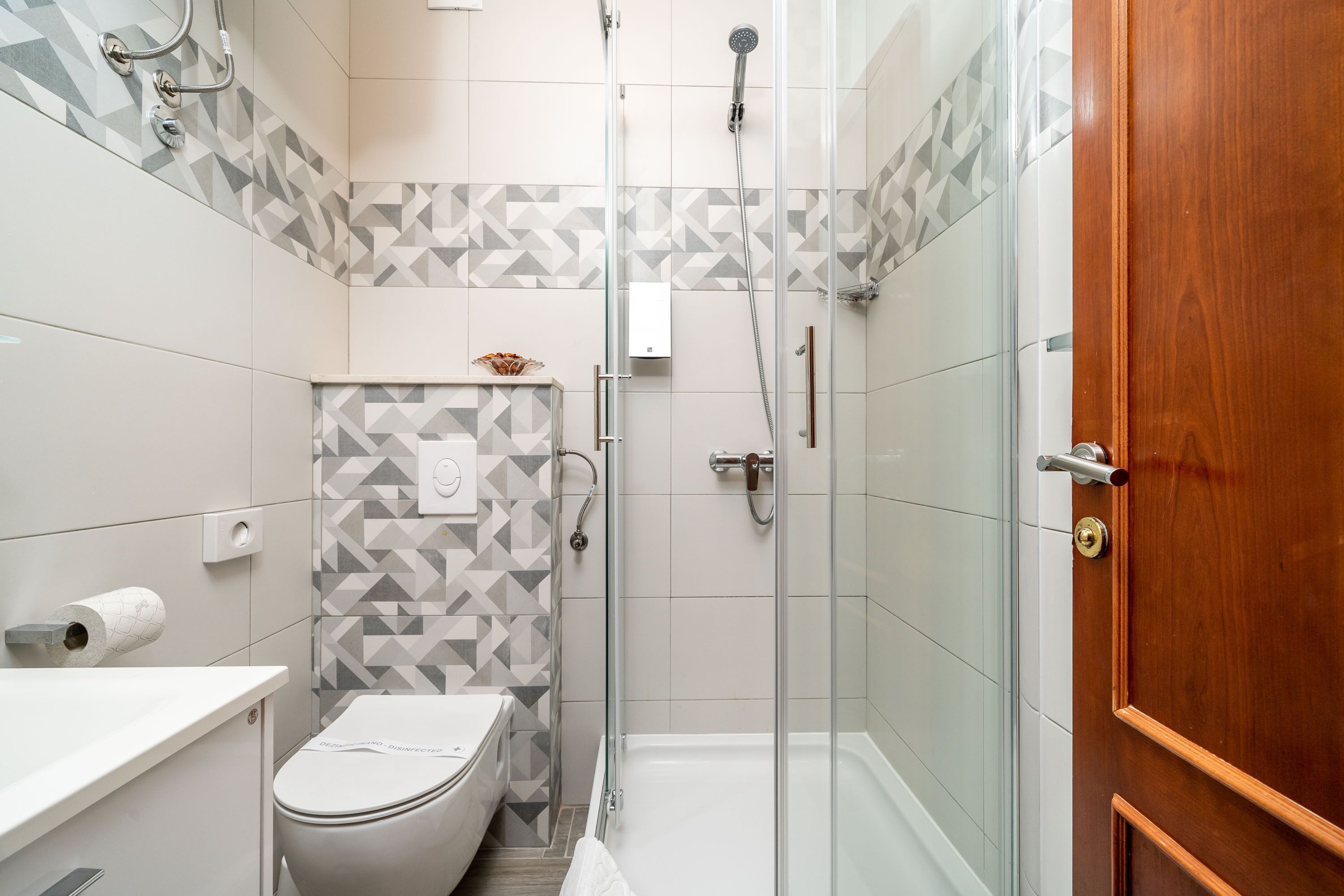 A modern bathroom with a toilet, shower, and a wooden door.
