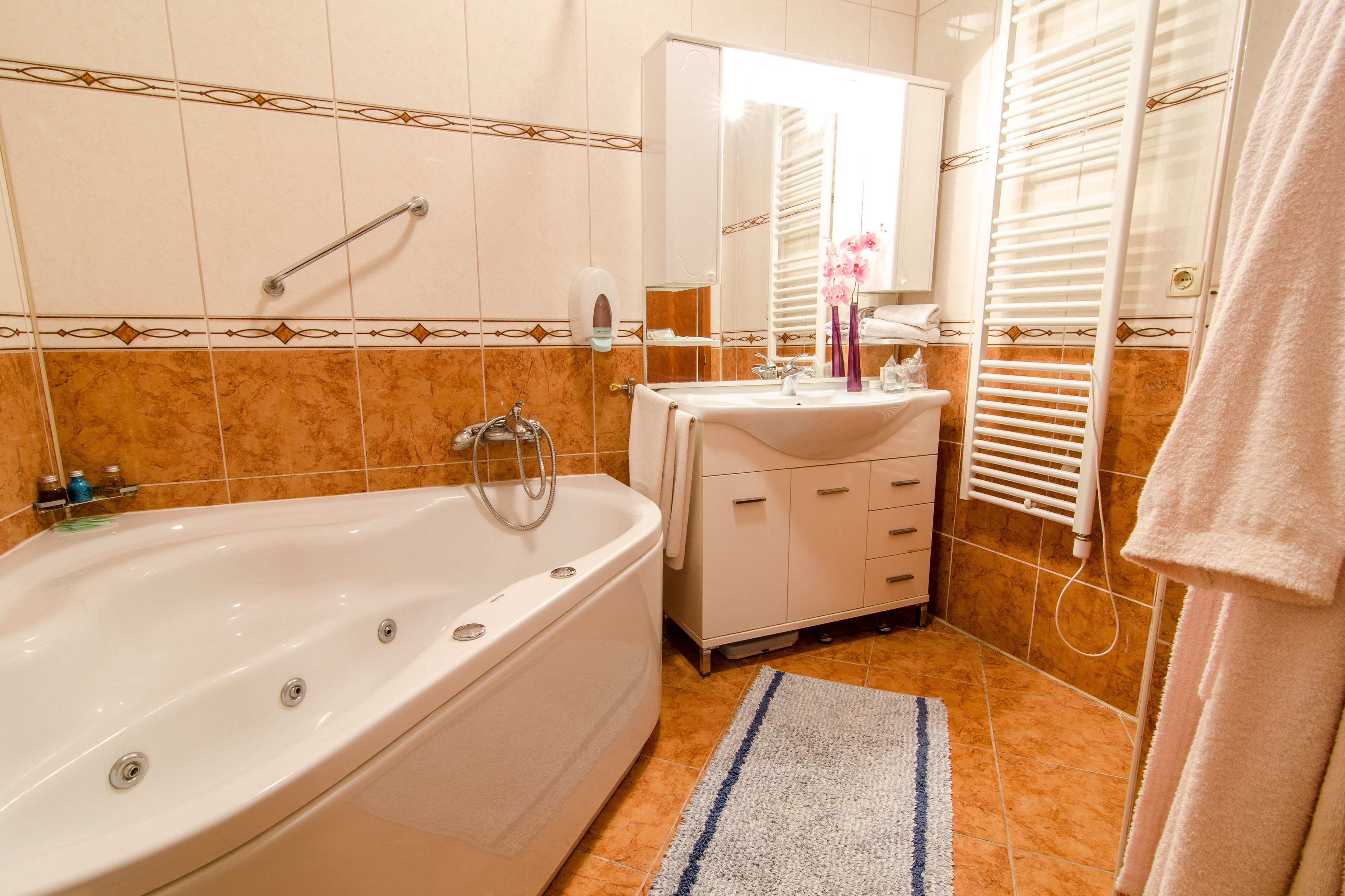 A bathroom with a bathtub, a sink, a mirror, and a towel rack.