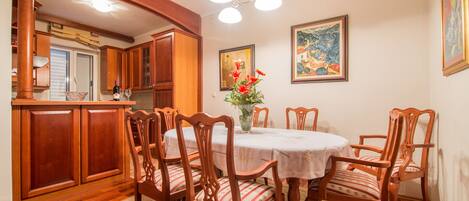 Un comedor con sillas y una mesa de madera, una cocina con armarios de madera y un cuadro en la pared.