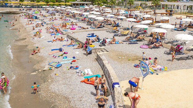 A crowded beach with people sunbathing and swimming, umbrellas, and beach chairs. - Hotel Dubrovnik (Dubrovnik)