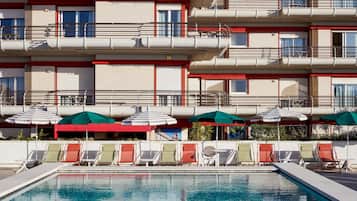 Ein Hotel mit Poolbereich, mehreren Balkonen und Außenbereich mit Sonnenschirmen.