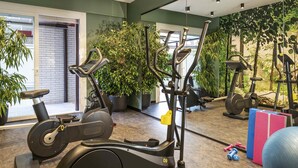 Un gimnasio con bicicletas estáticas, máquinas elípticas y pesas sueltas.