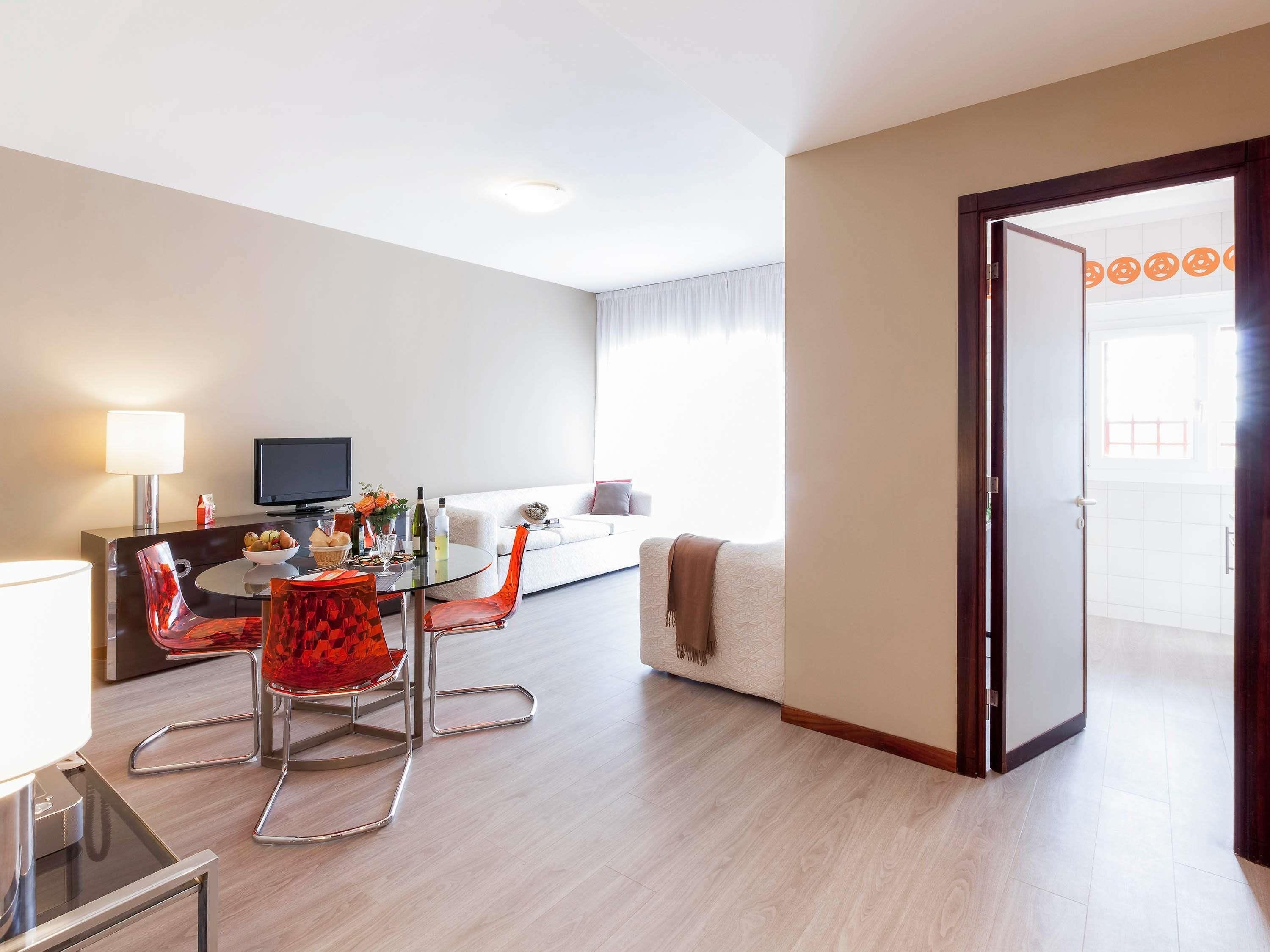 Una camera d'albergo moderna con zona pranzo, divano e televisione.