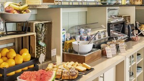 Un bufé con diversas opciones de comida, incluyendo frutas, pasteles y bebidas.