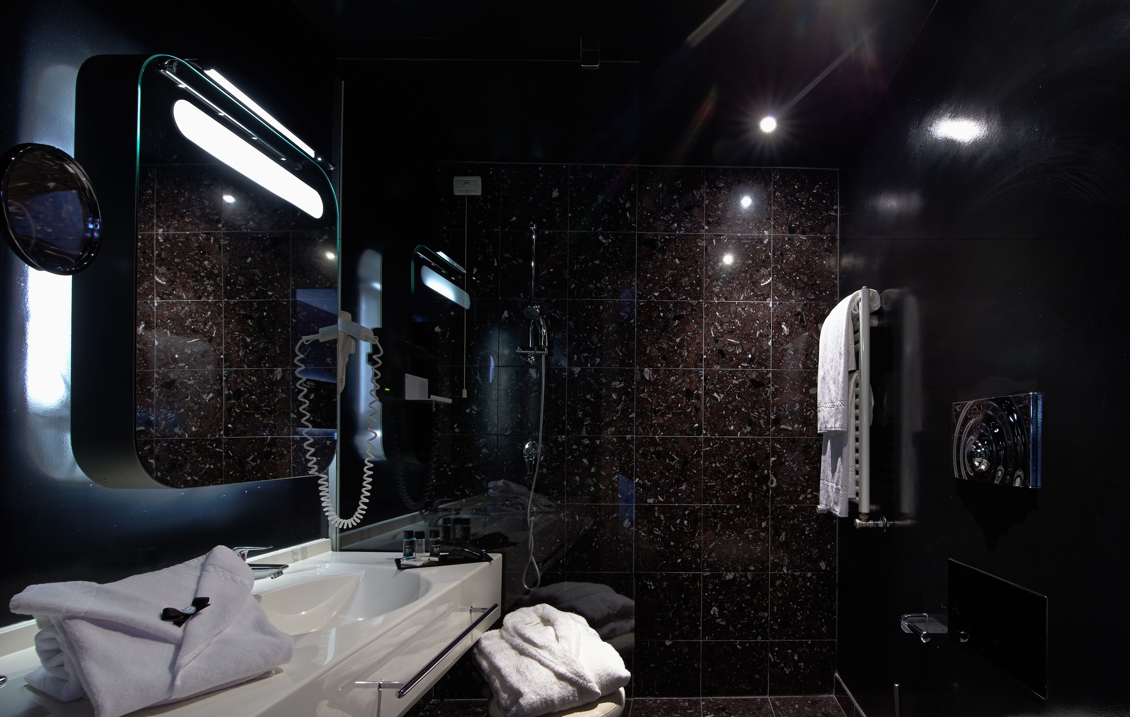Un baño moderno con un espejo grande, un lavabo blanco y un perchero para toallas.