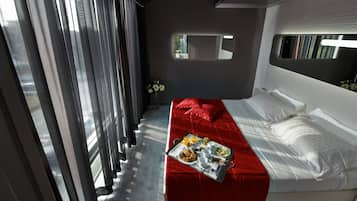 Ein modernes Hotelzimmer mit einem Bett, einer roten Couch und einem Frühstücksbrett auf dem Boden.
