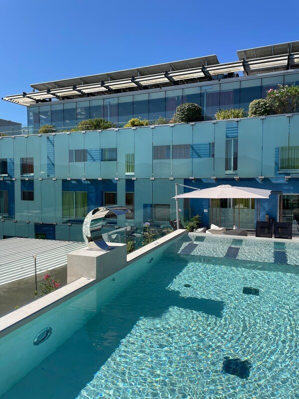 A modern building with a rooftop pool, glass balconies, and solar panels.