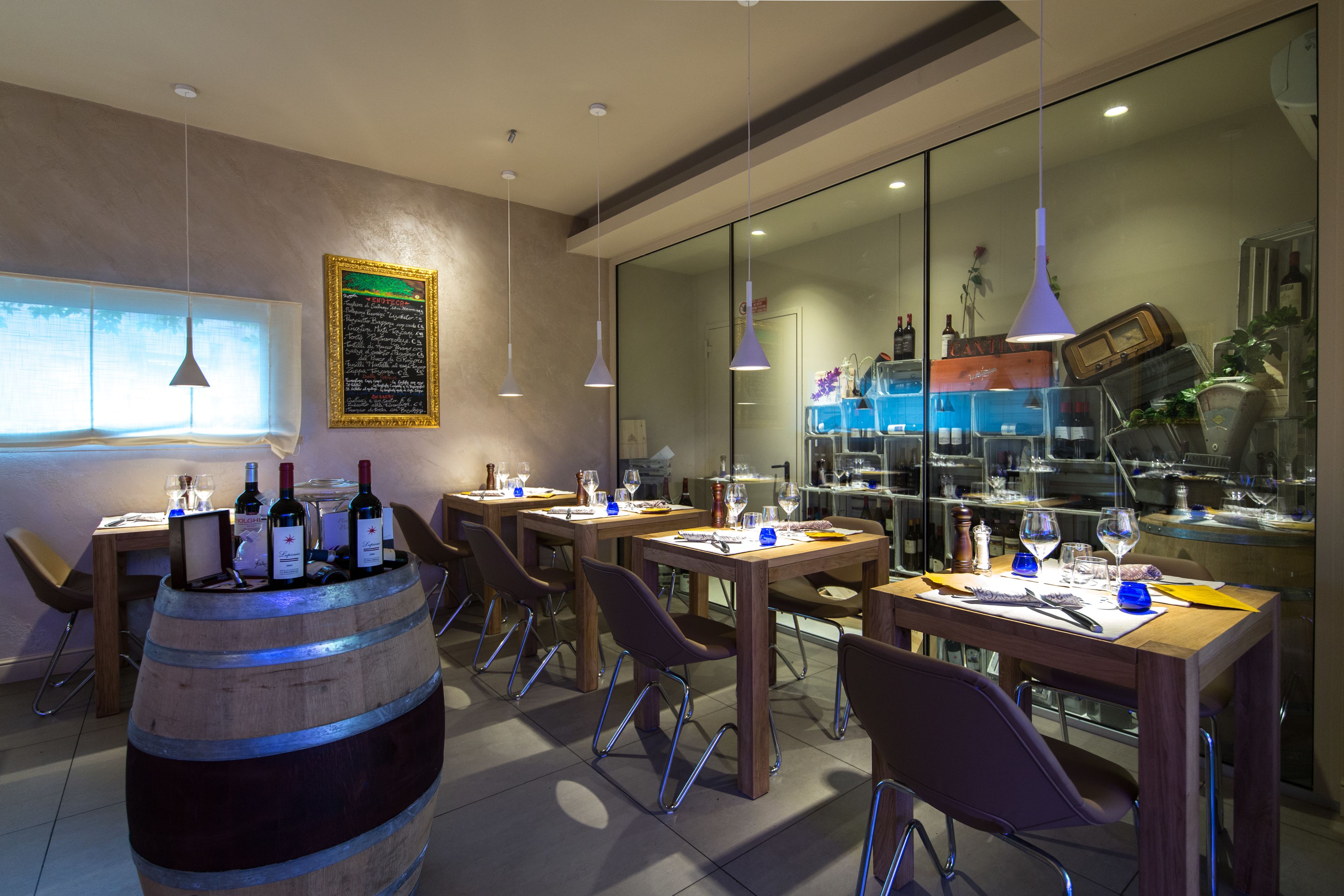 A restaurant with wooden tables and chairs, wine bottles, and a large barrel.
