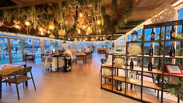 Ein Restaurant mit modernem Interieur, das Pendelleuchten, eine Weinauslage und einen Blick ins Freie bietet.