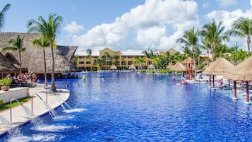 Ein großer Swimmingpool mit Palmen und strohgedeckten Gebäuden, umgeben von einem Hotel.