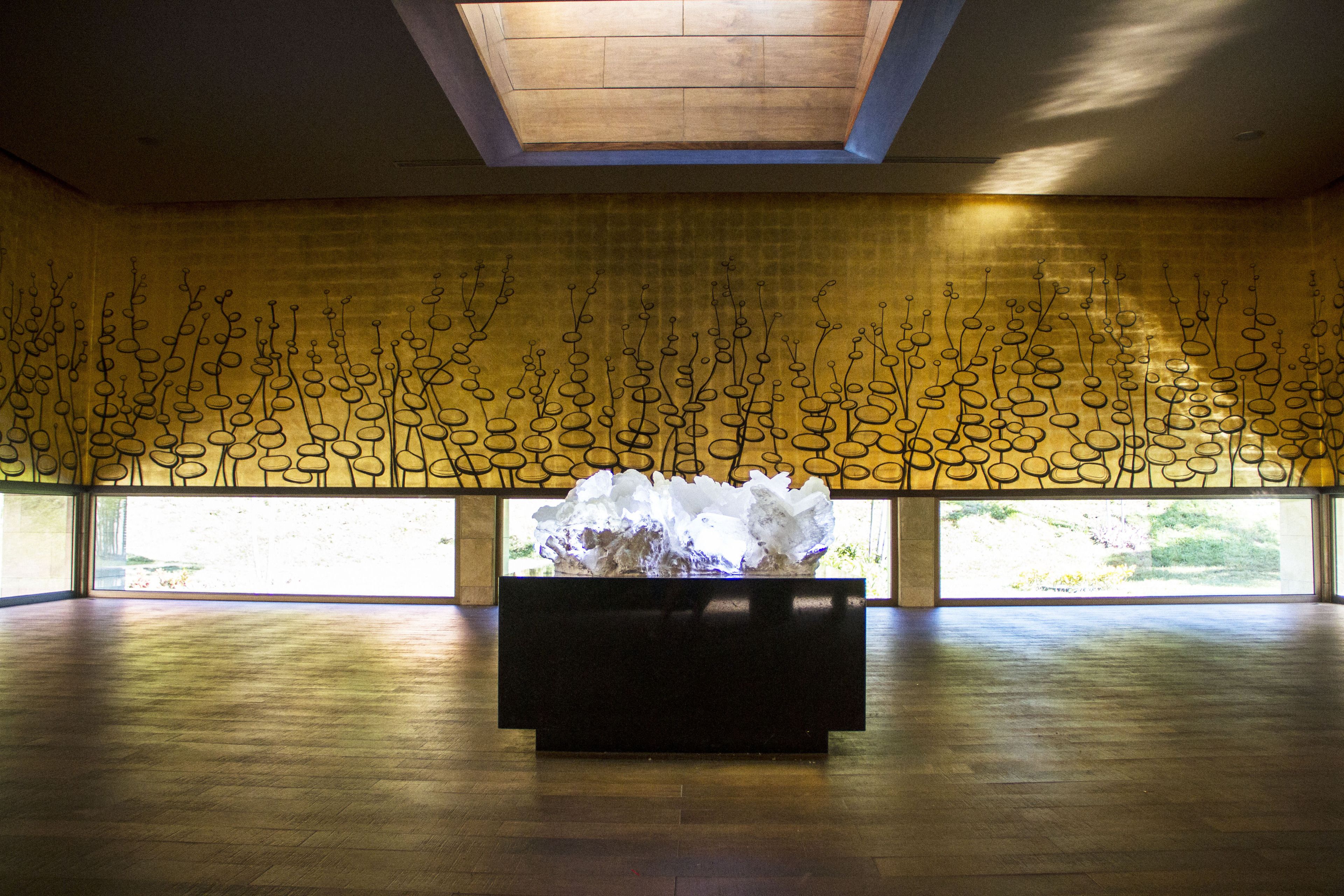 A spacious room with a large window, a wooden floor, and a central sculpture.