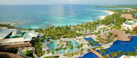 A resort with multiple swimming pools, palm trees, and a beach view.