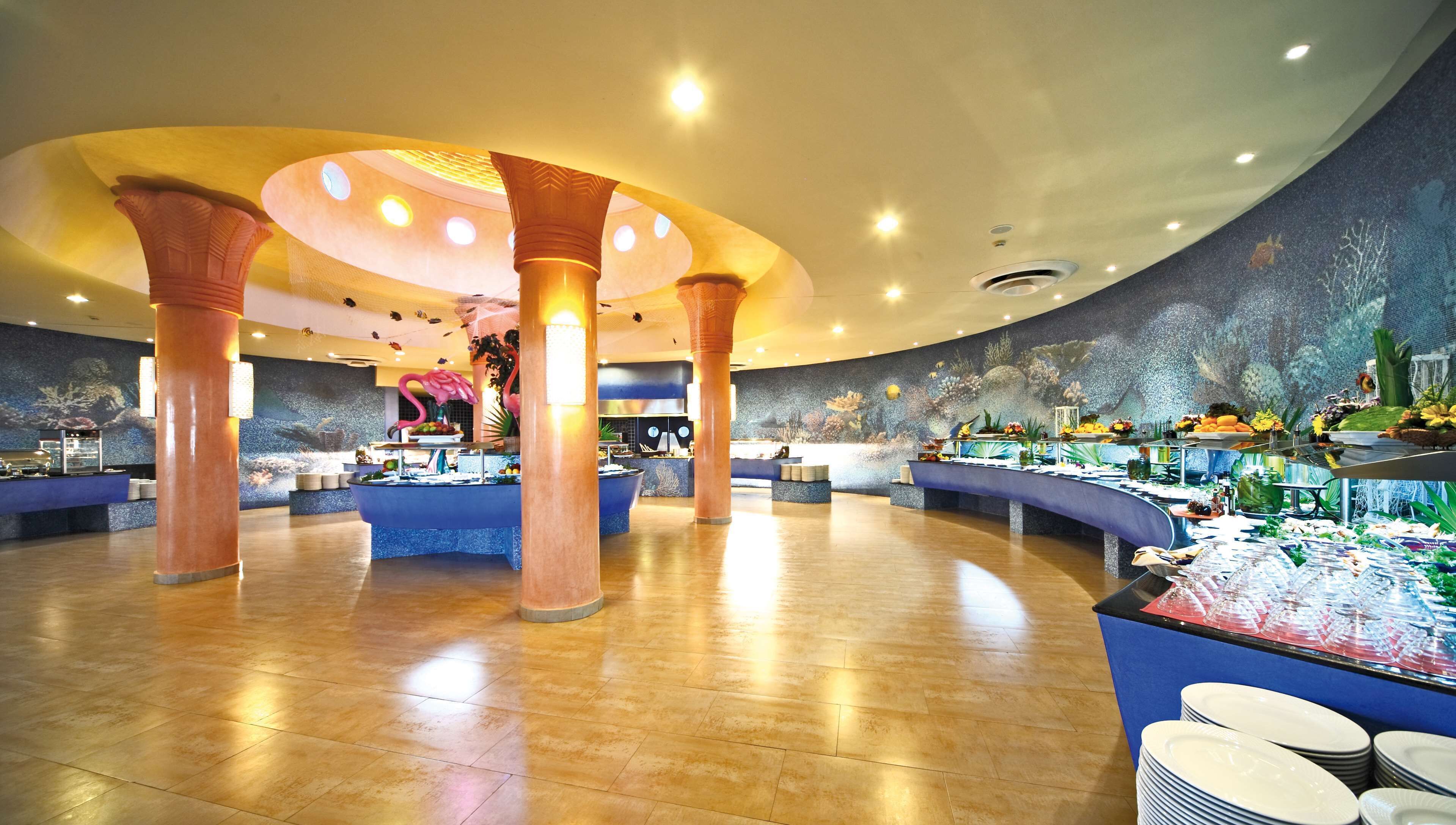 Eine geräumige Lobby mit einer zentralen Insellounge, verschiedenen Sitzbereichen und einer dekorativen Decke.