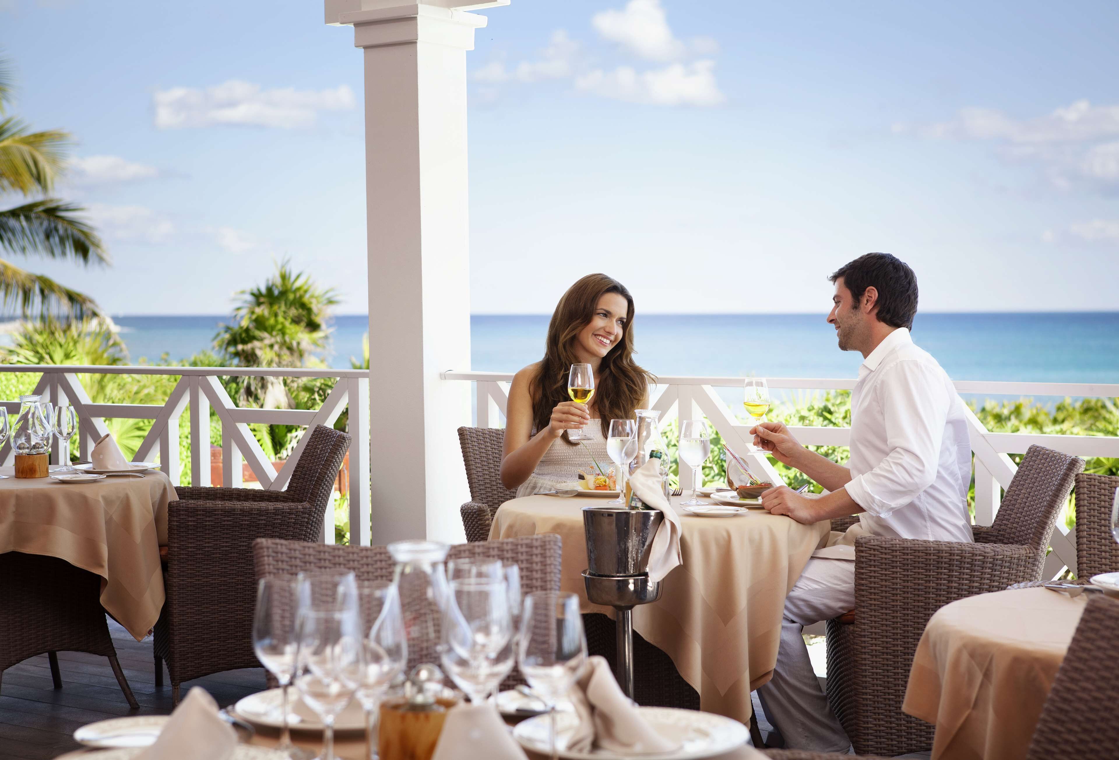 Un couple est assis à une table en plein air, profitant de la vue sur l’océan.