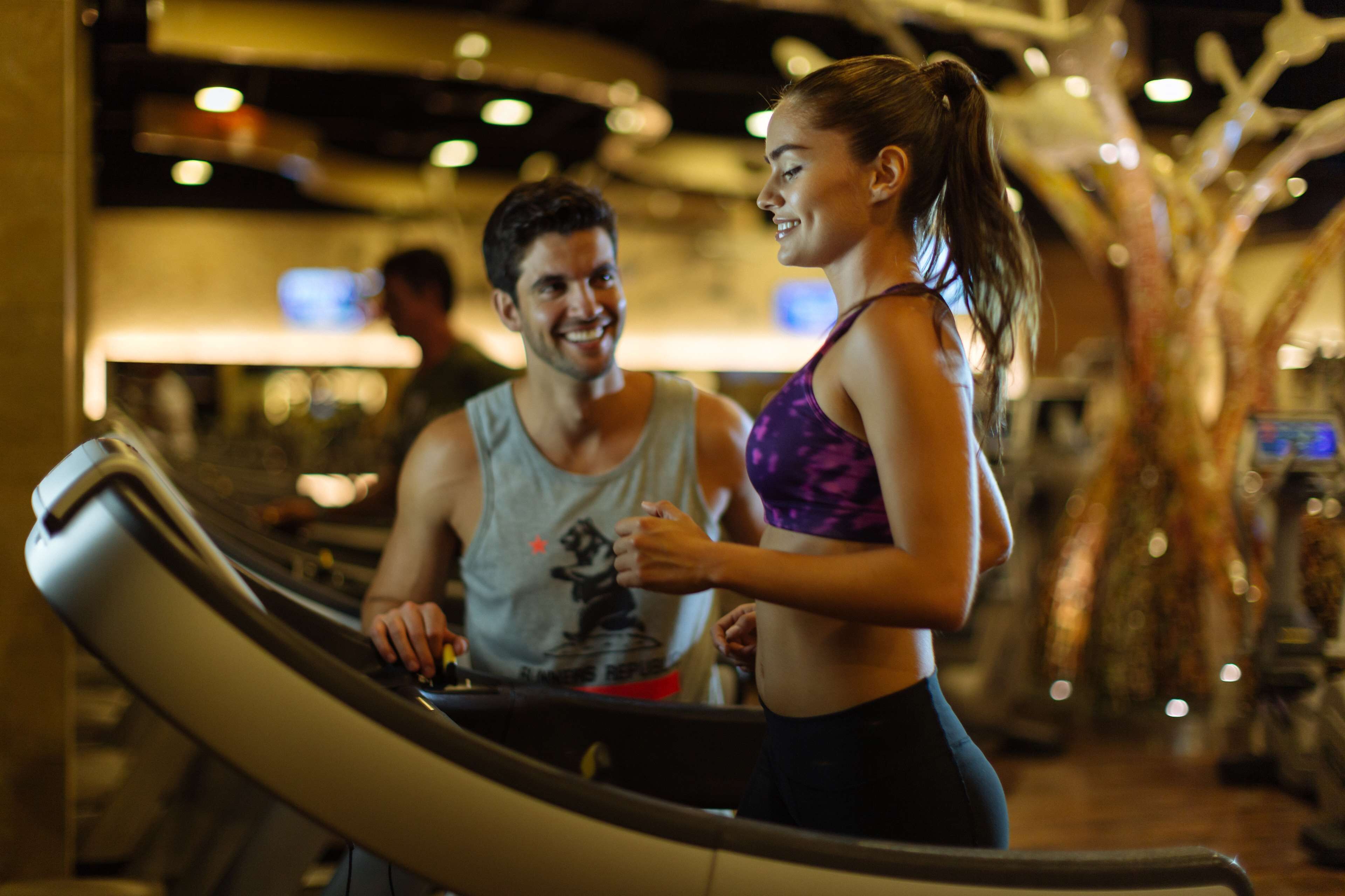 A gym with exercise equipment and a person using a treadmill.