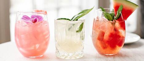 Tres vasos de cócteles con hielo, adornados con hojas de menta y una rodaja de sandía.