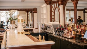 A bar area with a marble countertop, wine glasses, bottles, and a coffee machine.