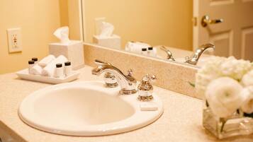 A hotel bathroom with a sink, mirror, and toiletries.