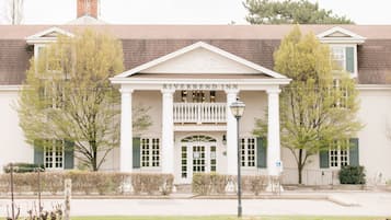 Un bâtiment doté d’une entrée centrale encadrée de colonnes, d’une enseigne indiquant « RIVERBEND INN » et d’une pelouse bien entretenue à l’avant.