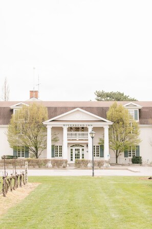 A building with a central entrance framed by columns, a sign reading "RIVERBEND INN," and a well-maintained lawn in front.