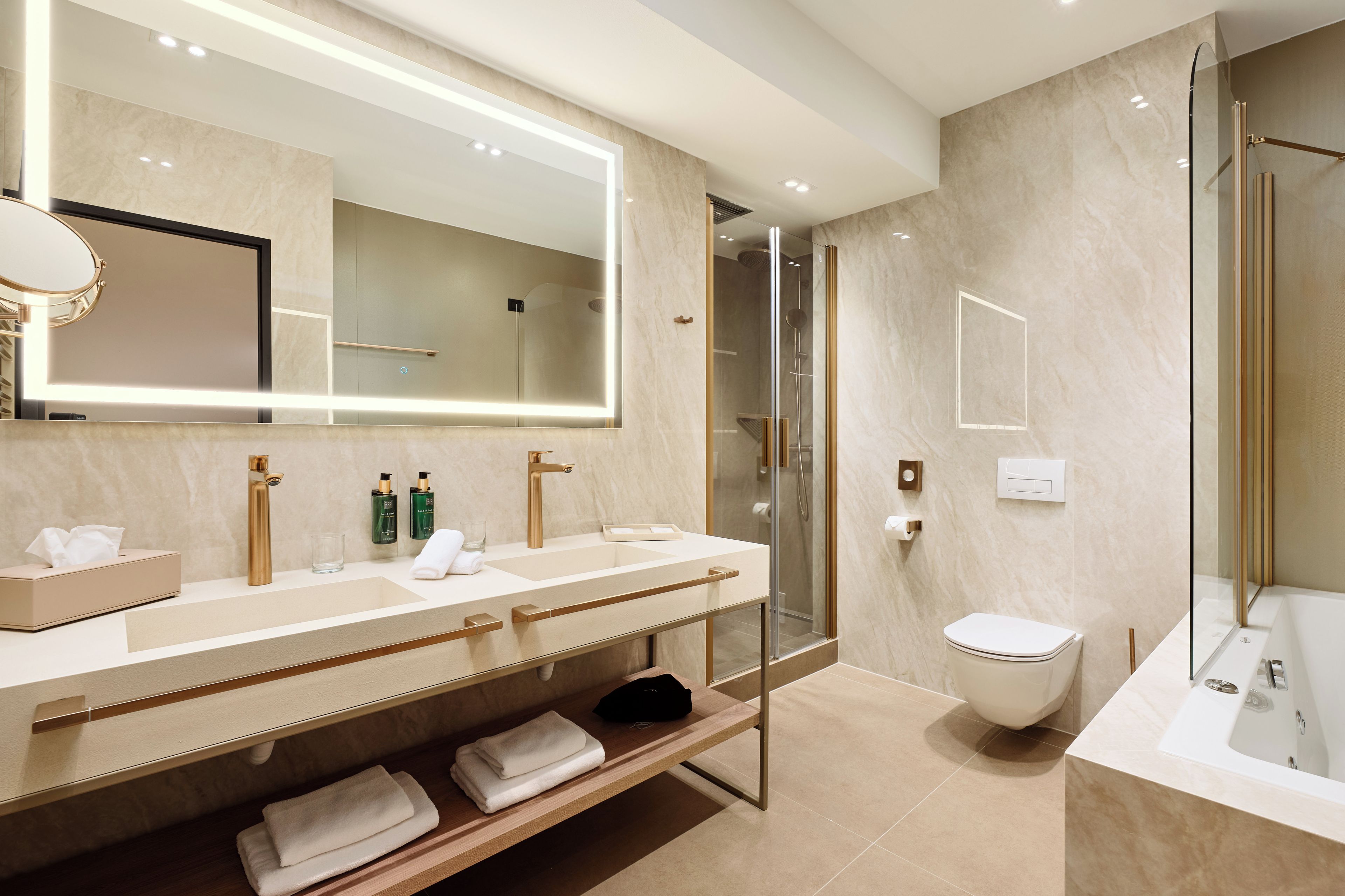 A modern bathroom with a large mirror, dual sinks, a shower, and a toilet.