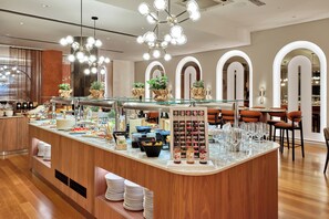 A modern breakfast bar with glass display cases, a variety of food items, and a selection of beverages.