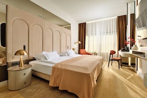 A modern hotel room with a large bed, a desk, and a chair.