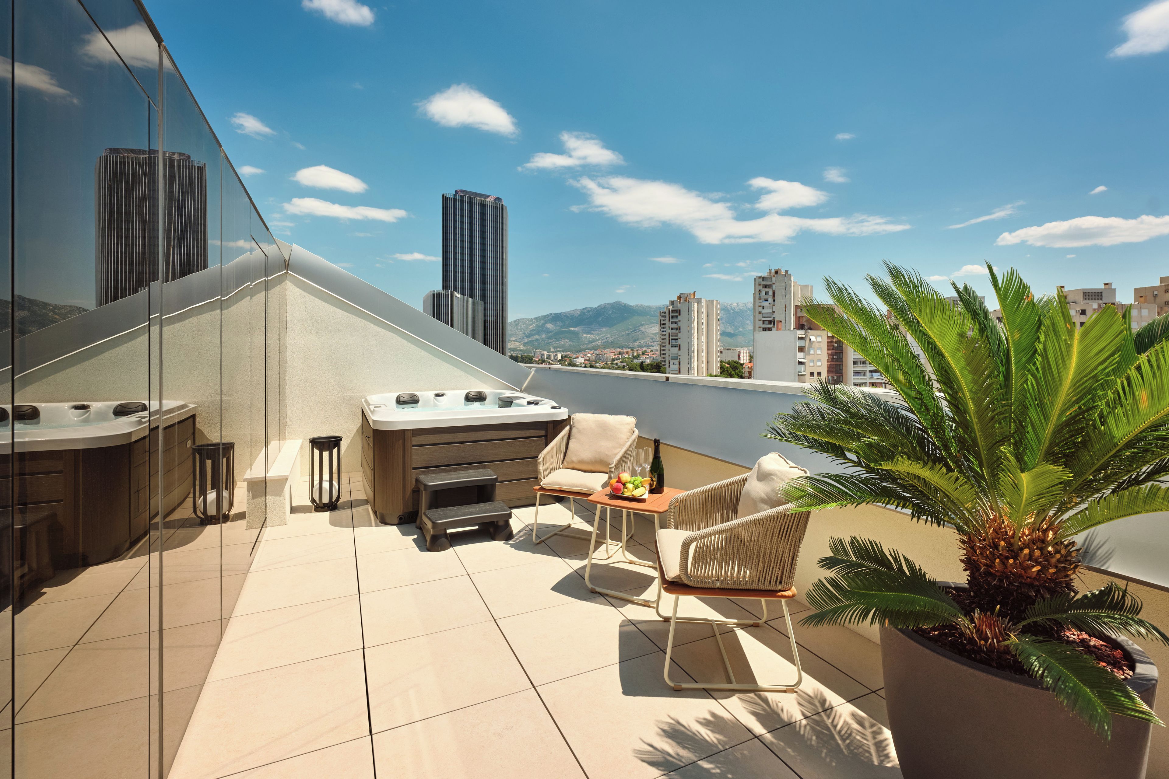 A rooftop terrace with a hot tub, seating area, and a view of the cityscape.