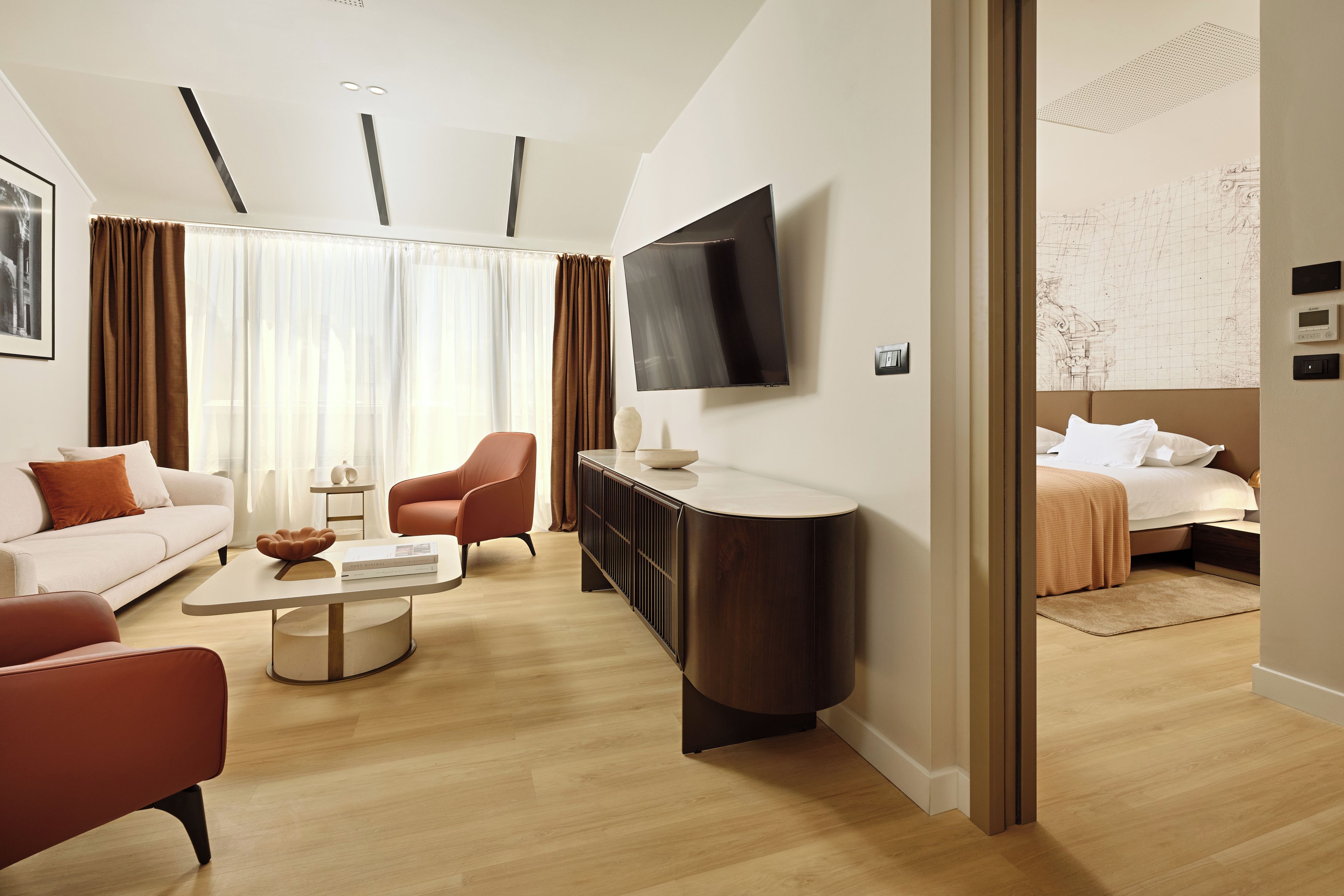 Una habitación de hotel moderna con una televisión de pantalla plana, un sofá, una silla, una mesa de centro y una cama.
