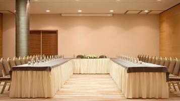 Un salón de conferencias con una larga mesa, sillas y un centro de mesa decorativo.