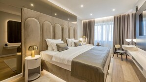 Habitación de hotel moderna con una cama grande, mesitas de noche, un televisor y una zona de estar.
