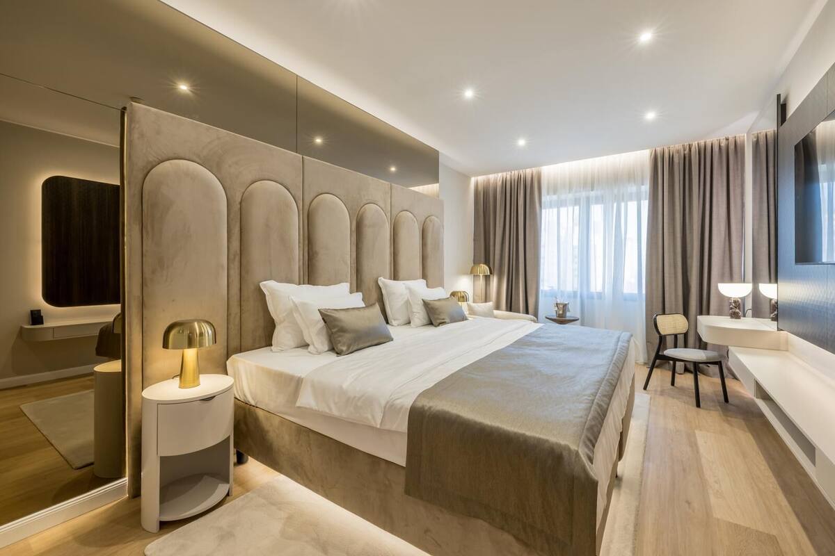 Habitación de hotel moderna con una cama grande, mesitas de noche, un televisor y una zona de estar.