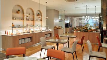 Un restaurante moderno con una barra central, varias zonas de estar y una amplia variedad de comida y bebidas.