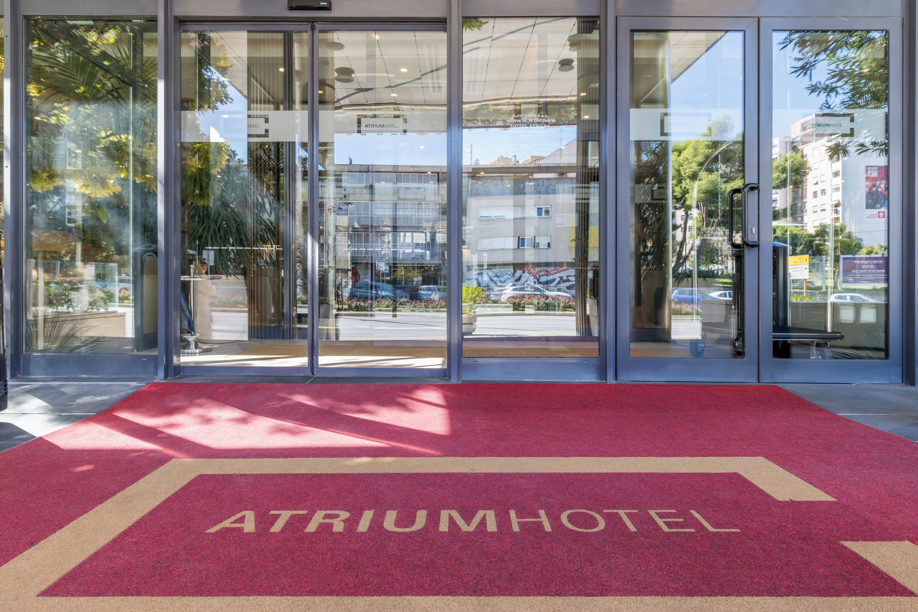 A hotel entrance with a red carpet and glass doors.