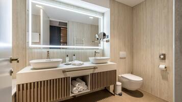 Un baño moderno con dos lavamanos, un inodoro y un mueble de tocador con toallero.
