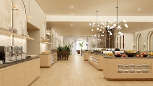 Una cocina de hotel moderna con una isla central, máquinas de café y una presentación de frutas.