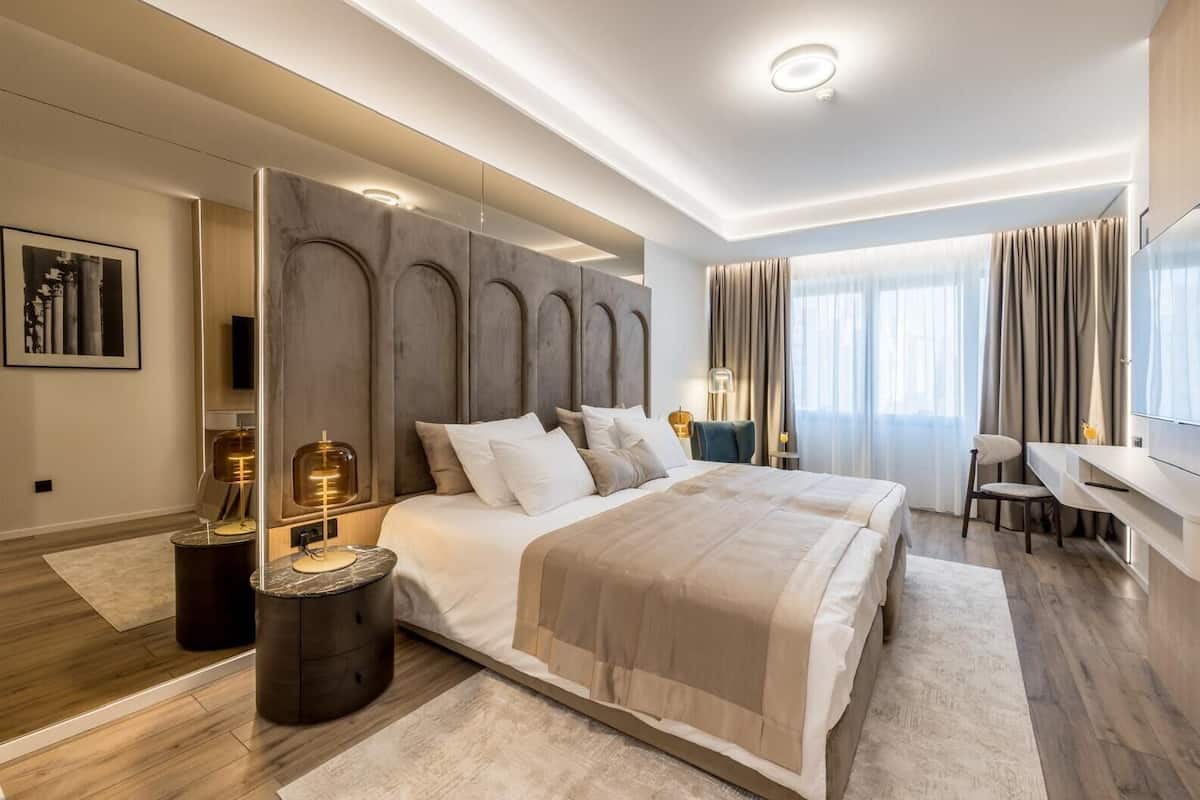 Una habitación de hotel moderna con una cama grande, un escritorio y una televisión.
