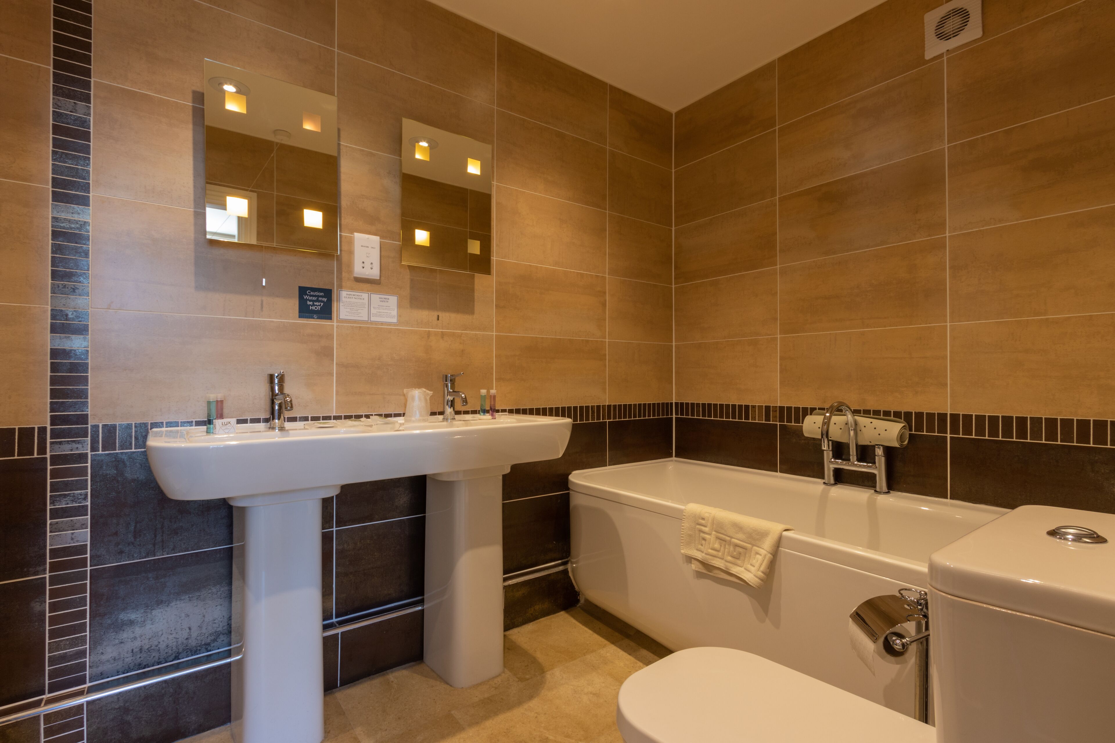 Een badkamer met een wastafel, spiegel, badkuip en toilet.