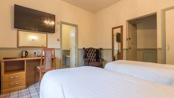 A hotel room with two beds, a desk with a chair, a television, and a mirror.