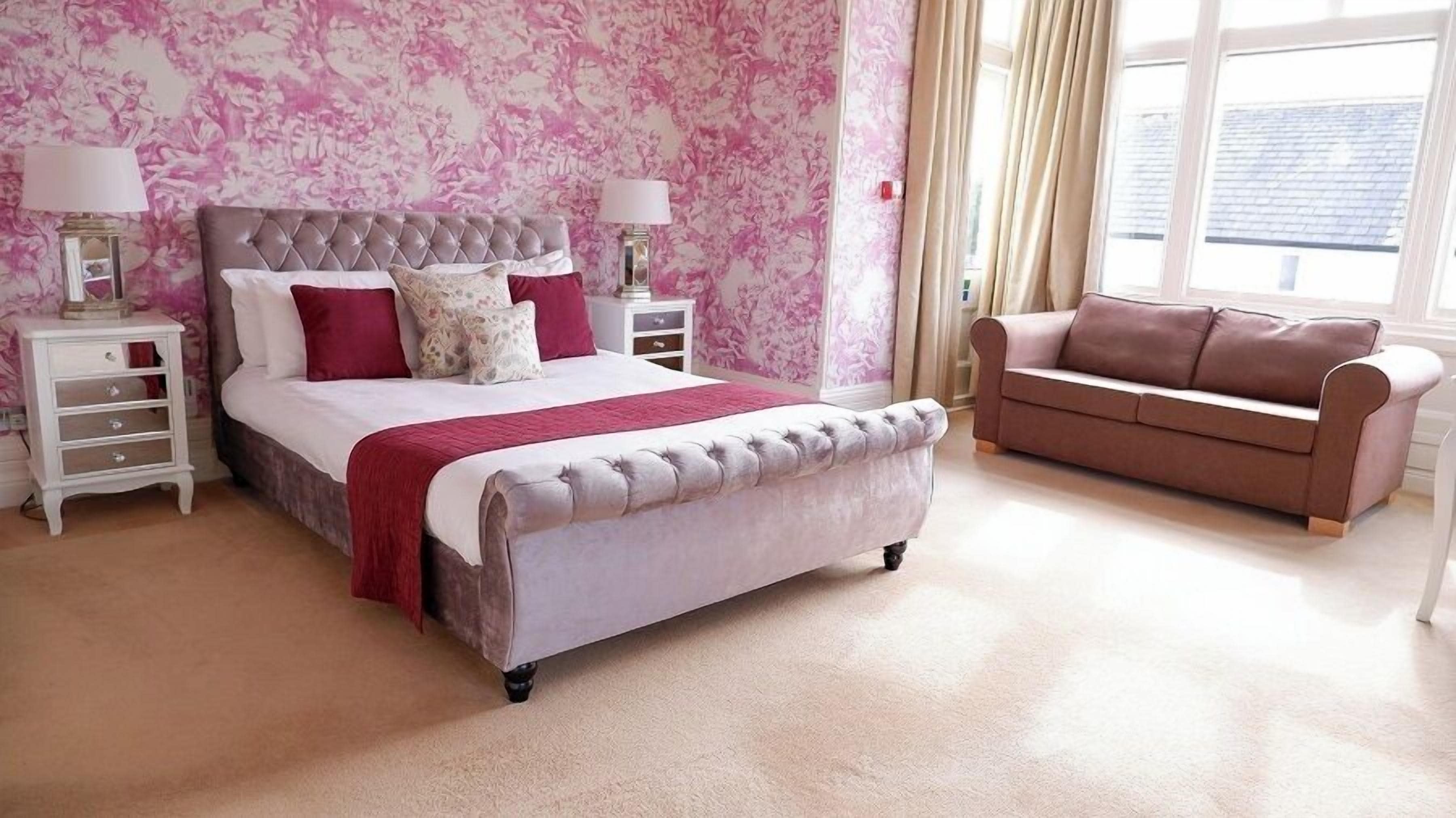 A bedroom with a tufted bed, a sofa, and a nightstand with lamps.